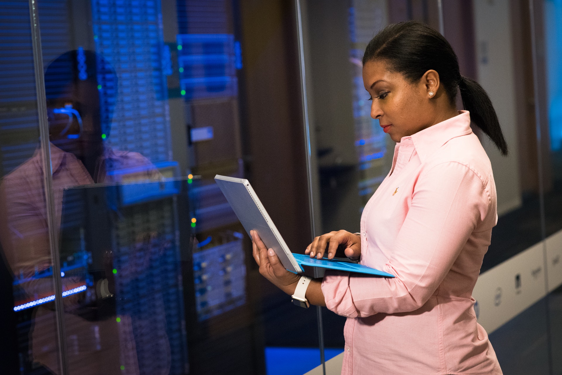 Woman standing with laptop in front of server