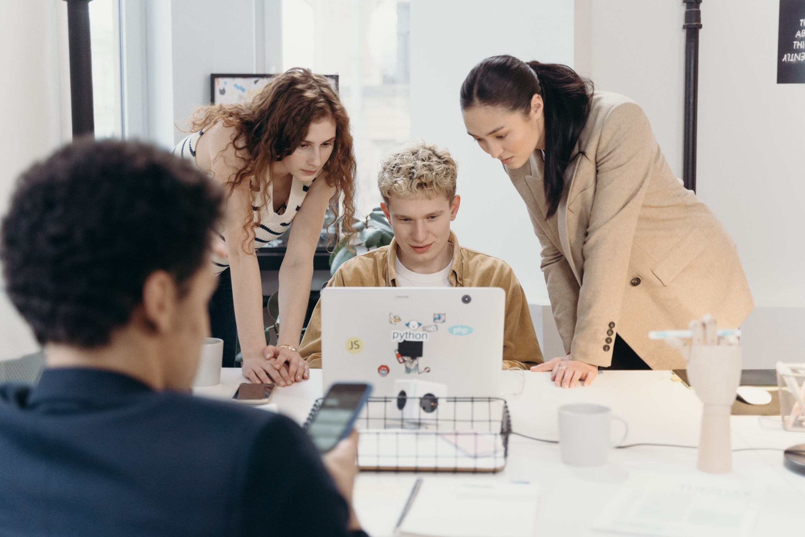 women standing beside man using laptop